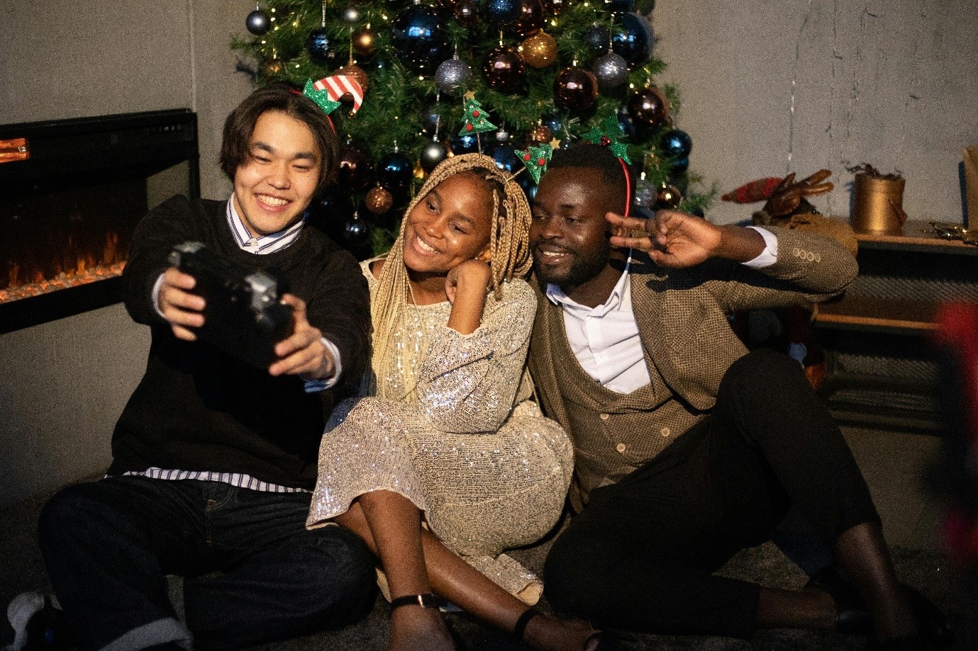 A group of people sitting next to a christmas treeDescription automatically generated